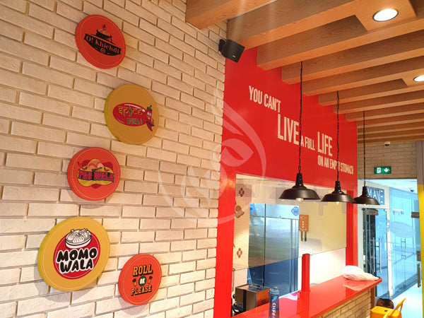 Brick wall with branded circular signs and a red interior wall with motivational quote.