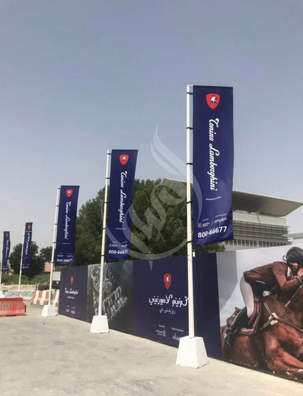 Row of blue banners with branding on poles against a clear sky.