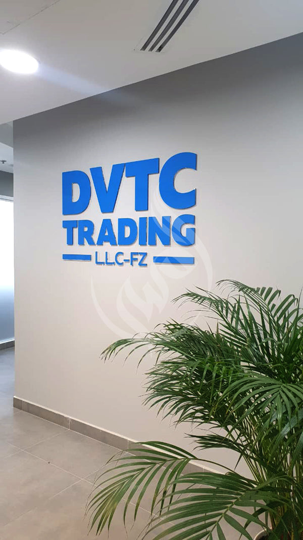 Wall with 'DVTC Trading LLC FZ' logo in a modern office setting with a plant.