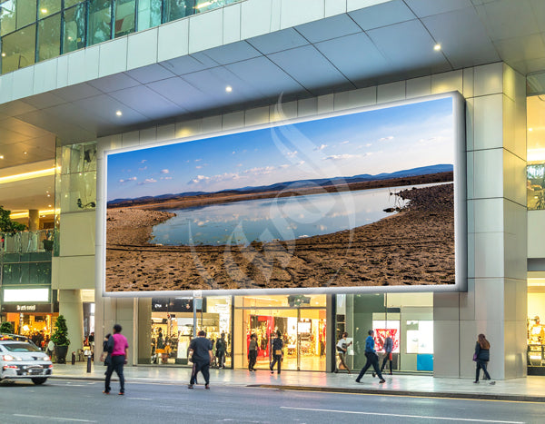 Large outdoor digital display on a building showing a scenic landscape.