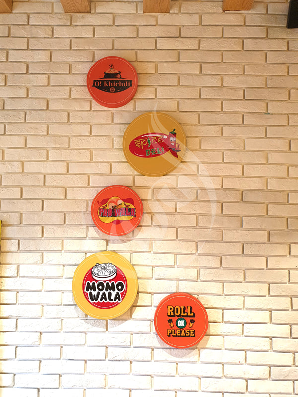 Five round signs with different text and logos on a tiled wall.