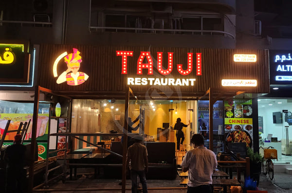 Restaurant exterior with 'TAUJI RESTAURANT' sign at night